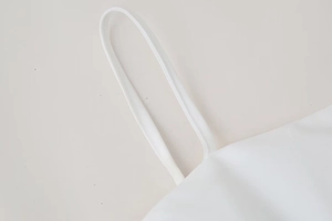 Close-up of a delicate spaghetti strap and fine stitching on a white poplin top