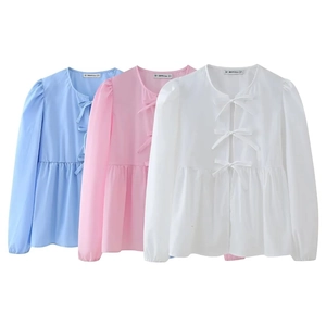 Detailed view of three cotton shirts in light blue, pink, and white with bow tie fasteners