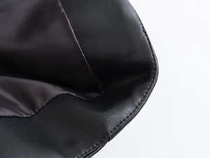 Détail du cuir grainé noir avec doublure en tissu marron et coutures précises