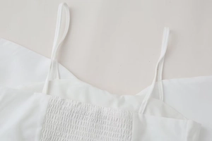 Detail of white poplin top featuring elastic smocked back and delicate spaghetti straps