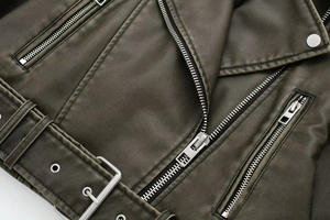 Detail of vintage faux leather biker jacket featuring silver zippers and belted waist
