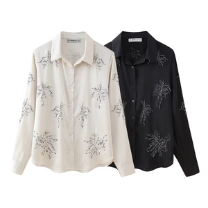 Macro detail of beadwork and floral embroidery on glossy silk-like shirts in black and white