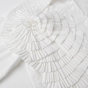 Detailed view of white shirt featuring intricate 3D floral ruffles and pleated design