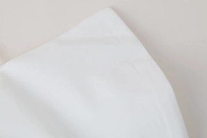 Close-up detail of white poplin fabric showing high-density cotton texture and fine stitching
