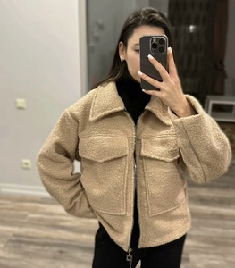 Detail of beige sherpa jacket with metal zipper and large utility chest pockets