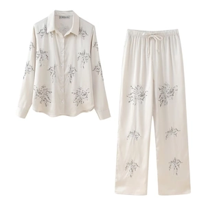 Detailed flat lay of cream embroidered satin shirt and drawstring trousers set