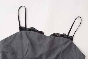 Detail of grey textured fabric with delicate black lace trim and thin straps