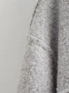 Close-up of oatmeal faux shearling fabric showing soft curly texture on short jacket