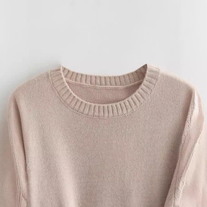 Close-up of a pink knit short-sleeve top featuring a ribbed crew neck and fine texture
