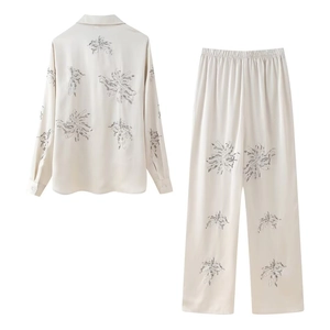 Detail of beaded embroidery on cream silk loungewear set with abstract floral patterns