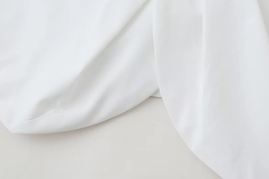 Detail of white poplin fabric showing gathered texture and crossover bow design