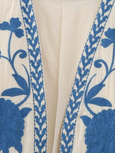 Close-up of off-white linen fabric with blue vintage floral embroidery detail