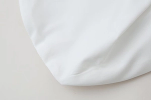 Detailed macro view of white poplin fabric texture and high-quality sewing of the top