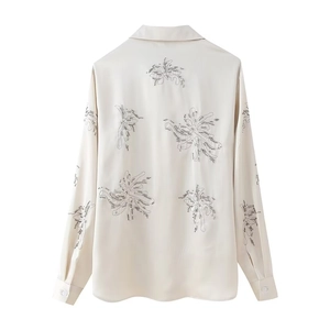 Detailed embroidery and beaded floral patterns on the back of a cream satin shirt