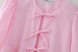 Detail of pink summer shirt with three bow-tie closures and round neckline texture