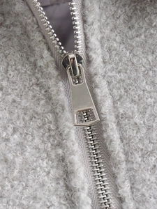 Macro shot of silver metal zipper puller and soft grey fleece fabric on a women jacket