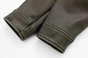 Detailed macro view of dark brown PU leather jacket cuffs with vintage grain and stitching