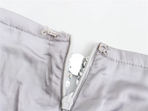 Detailed macro shot of the silver sequin skirt showing a white zipper and metal hook closure