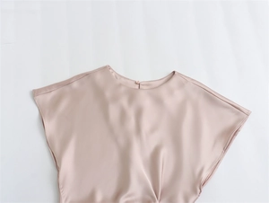 Gros plan détaillé du tissu en satin champagne montrant la texture lisse et le bouton