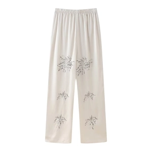 Detailed view of ivory satin wide-leg trousers featuring elegant silver sequin floral embroidery