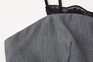 Macro detail of dark grey twill fabric featuring delicate black lace trim on the neckline