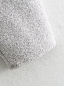 Detailed close-up of light gray sherpa fleece texture and hem stitching on a jacket