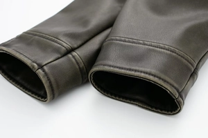 Close-up of vintage brown faux leather jacket sleeve featuring durable reinforced stitching