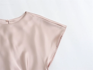 Détail de la robe en satin rose champagne avec bouton au dos et texture de soie lisse