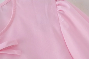 Detail of light pink blouse featuring pleated puff sleeves and a classic round neckline