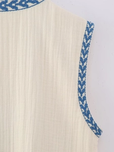 Detail of vintage ethnic blue embroidery on a cream cotton linen sleeveless vest