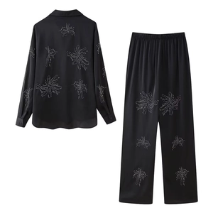 Detail of elegant black satin suit with intricate beaded floral patterns and rhinestones