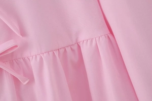 Detail of pink woven fabric with pleated textures and delicate side bow tie-up design