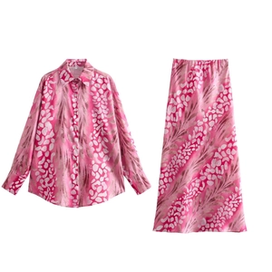 Detailed flat lay of pink floral shirt and midi skirt set with white leaf patterns