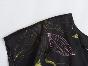 Detail of elegant black satin fabric with gold and pink leaf prints on the shoulder