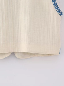 Close-up of geometric embroidery and natural linen texture on a retro summer vest