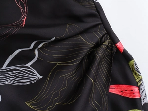 Detail of floral print on black satin fabric with intricate ruched side stitching