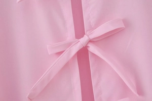 Detail of pink cotton shirt featuring elegant bow tie closure and premium stitching