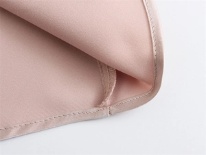 Vue macro des coutures fines et de la texture satinée sur une robe d'été mauve