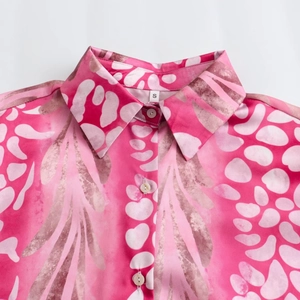 Close-up of shirt collar with pink abstract leaf print and white button details