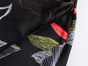 Detail of floral print satin fabric with smooth texture and shiny finish on black midi dress