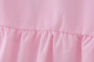 Detailed macro shot showing pink ruffled fabric texture and neat stitching on the shirt
