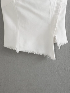 Dettaglio dell'orlo asimmetrico sfrangiato su tessuto di cotone twill bianco elegante