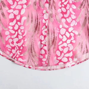 Close-up of pink leopard print shirt featuring curved hem and three white pearl buttons