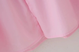 Detail showing the fine stitching and hem of the pink bow cardigan fabric in macro view
