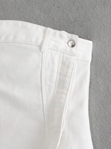 Dettaglio ravvicinato del tessuto denim bianco con cuciture premium e bottoni metallici