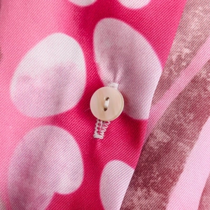 Close-up of pink polka dot fabric showing twill texture and single white button detail