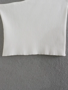 Macro shot of white ribbed knit fabric texture on the hem of a sleeveless summer top
