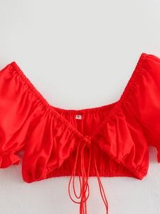 Detail of red off-shoulder top showing pleated neckline, tie-up chest, and size S label