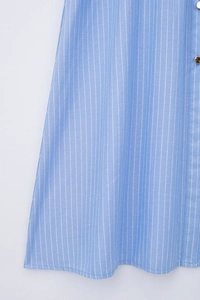 Détail de robe à rayures bleu clair avec bouton doré et coutures de haute précision