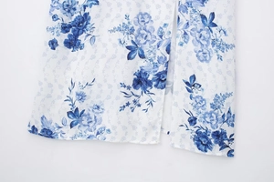Close-up detail of white floral print dress featuring a side slit and blue flower pattern